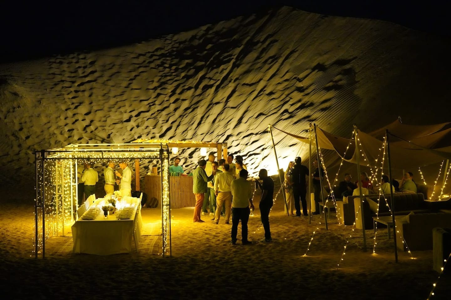 Private luxury desert camp and dining setup under illuminated dunes